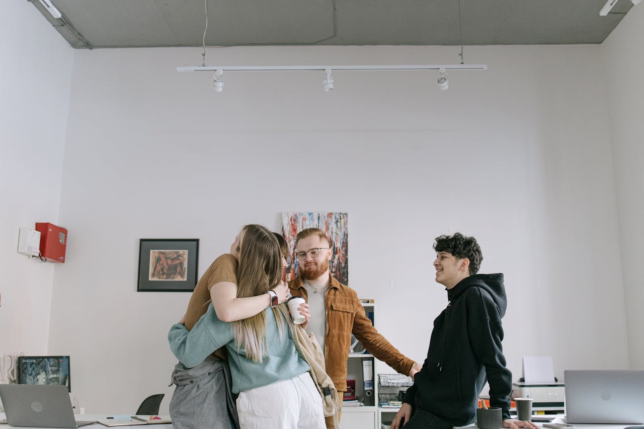A group of young professionals embracing in a modern office setting, showcasing teamwork and camaraderie.